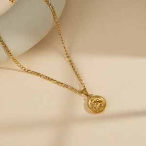 Macro detail of gold Figaro chain and round Taurus zodiac coin pendant for men