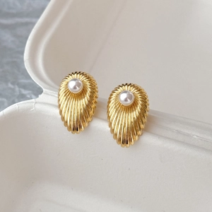 Vintage gold shell earrings with center white pearl on a minimalist beige background