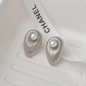 Macro view of vintage silver shell earrings with pleated texture and central pearl accent