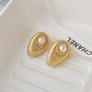 Close-up of vintage gold teardrop earrings featuring a centered white pearl inlay