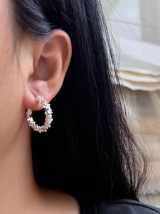 Close-up of silver C-shaped hoop earrings with textured crushed silver pebble surface