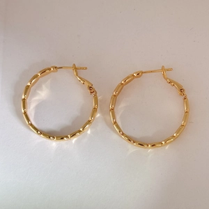 Fashionable golden bamboo-style geometric hoop earrings with polished metal finish