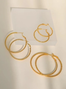 Detailed view of three pairs of gold twisted hoop earrings in large, medium, and small sizes