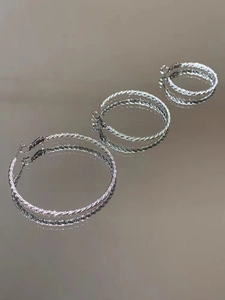 Detailed view of silver twisted rope hoop earrings set in three sizes with reflective finish