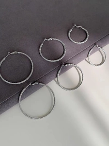 Detailed view of three pairs of silver-colored twisted hoop earrings in varying sizes