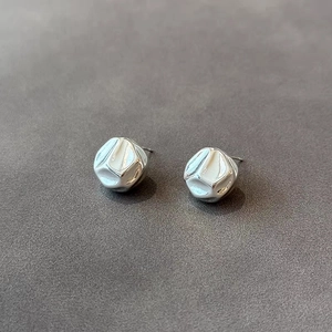 Macro detail of silver irregular geometric cube earrings with textured hammered finish