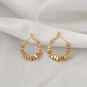 Élégantes boucles d'oreilles créoles dorées perlées avec design texturé sur soie blanche