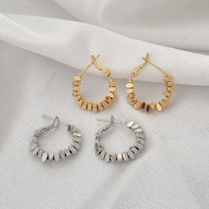 Boucles d'oreilles créoles texturées argent et or sur fond de tissu blanc élégant