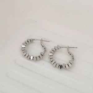 Gros plan détaillé des boucles d'oreilles créoles argentées à maillons perlés