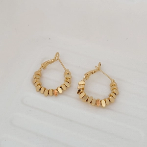 Vue détaillée des boucles d'oreilles créoles dorées à perles avec fermoir français