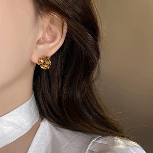 Macro detail of high-shine gold hollow spherical earrings on model with warm tones