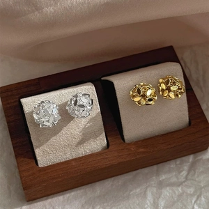 Close-up of gold and silver sphere stud earrings featuring textured metal sequins