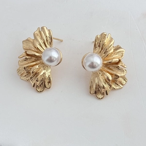 Détail de boucles d'oreilles feuilles de ginkgo dorées avec perle blanche au style rétro chic