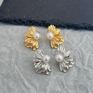 Détail de boucles d'oreilles florales plissées en or et argent avec perles centrales