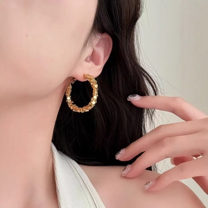 Chic oversized gold hoop earrings with sparkling scale texture shown on a female model