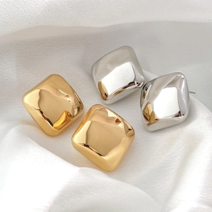 Boucles d'oreilles carrées polies en or 18 carats et argent sur tissu en soie blanche