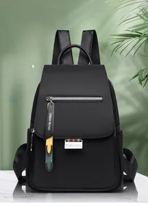 Détail d'un sac à dos noir étanche avec pendentif de mode sur fond de marbre vert