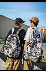 Outdoor shot of the manga print backpack featuring a green dinosaur plush keychain detail