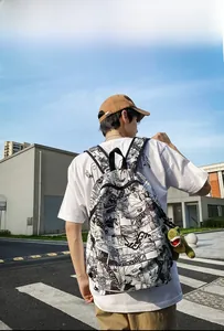Street view of black and white manga print backpack with a green dinosaur plush keychain