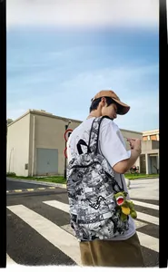 Close-up of manga print backpack with green dinosaur plush charm against blue sky