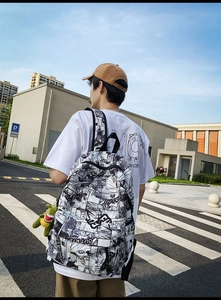 Street style shot of manga print backpack with green dinosaur plush charm accessory