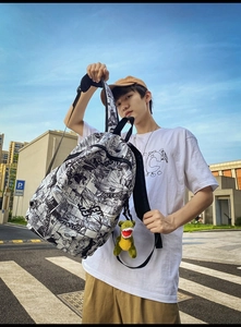 Detail of fashion backpack with black and white manga print and green dinosaur charm