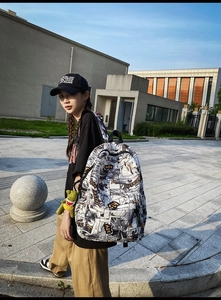 Close-up of comic-print backpack featuring street-style graffiti and green dinosaur charm