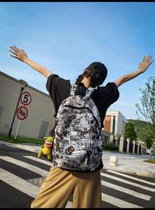 Outdoor shot of streetwear backpack featuring comic print and a green dinosaur pendant