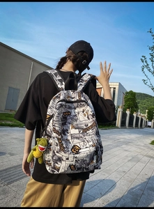 Close-up of comic print backpack with a cute plush dinosaur charm in a street setting