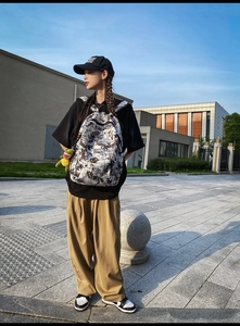 Street style backpack with comic print, yellow typography, and green monster charm