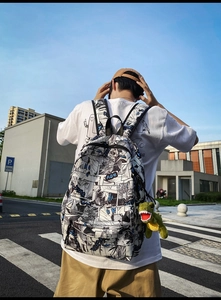 Detailed view of comic print backpack with a cute green dinosaur plush keychain