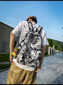 Detail of street style backpack with manga print and green plush dinosaur charm accessory