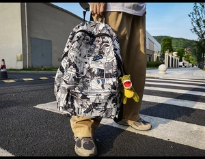 Detailed view of large black and white comic print backpack with dinosaur keychain charm