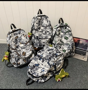 Close-up of comic print backpacks with green dinosaur plush charms and bold typography