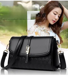 Detail of black lychee grain leather handbag with rhombus texture and gold buckle