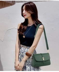 Detail of green leather shoulder bag featuring lychee texture and gold metal buckle lock