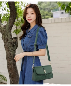 Detail of dark green leather crossbody bag with quilted texture and gold clasp