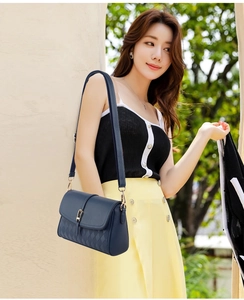 Detailed view of dark blue leather bag with litchi texture and gold metal buckle