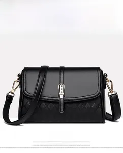 Close-up of black lychee leather crossbody bag with quilted pattern and gold buckle