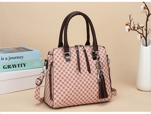 Detail of pink Boston bag with brown geometric print, tassel charm and cat pendant
