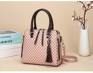 Detail of pink geometric printed handbag with dark brown handles and fringe tassel decor