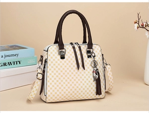 Detail of printed handbag featuring geometric pattern, round handles and tassel charm