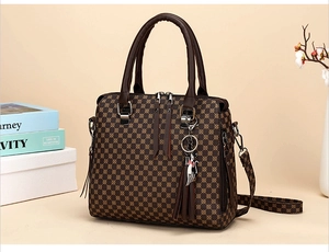 Detail of printed handbag with double zipper, tassel charm and adjustable shoulder strap
