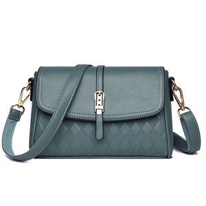 Detail view of greyish-blue textured leather handbag with quilt pattern and gold clasp