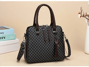 Detail view of double zippers and tassel charm on a gray geometric crossbody handbag