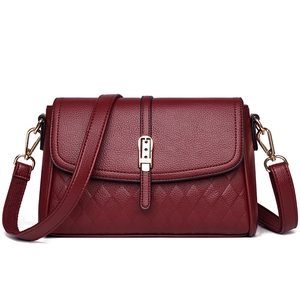 Detailed shot of dark red leather bag with litchi grain flap and quilted rhombus texture