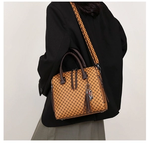 Detail of mustard yellow patterned tote bag with brown leather handles worn by a model