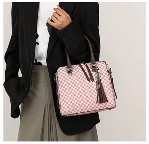 Detailed view of pink patterned tote bag with brown leather handles and tassel accent