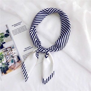 Detail of blue and white striped silk scarf tied in a knot on a white fabric background