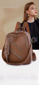Close-up of caramel brown PU leather backpack with multiple silver zippers and rivets